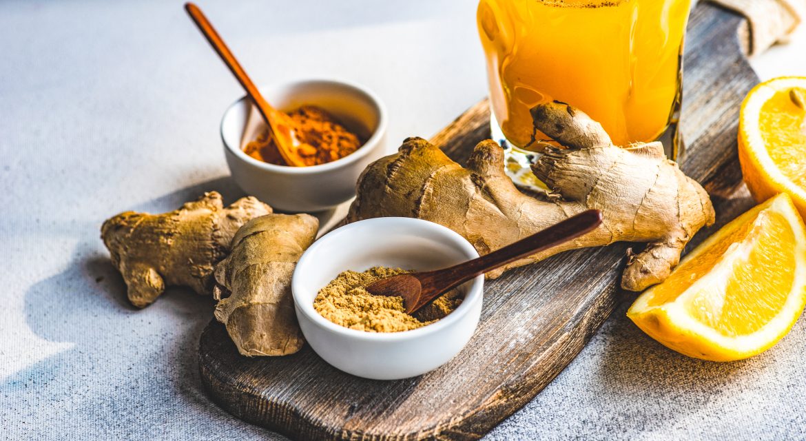 Fresh turmeric, ginger and orange drink with ingredients on a table