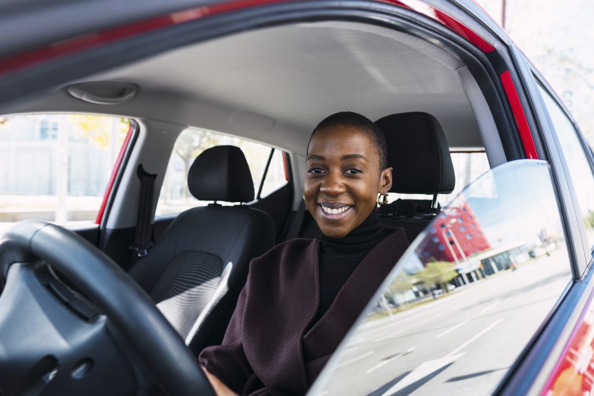 Happy young woman sitting in car Spells to win tenders