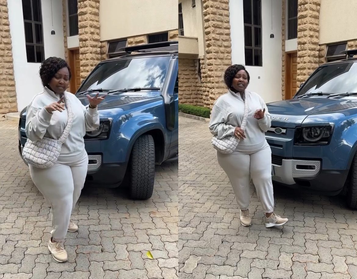 Millicent Omanga dances next to her new Land Rover Defender